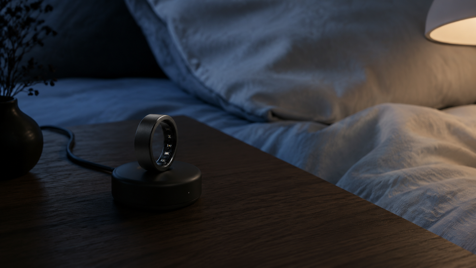 Matte black HealthRing resting on its charging dock on a nightstand